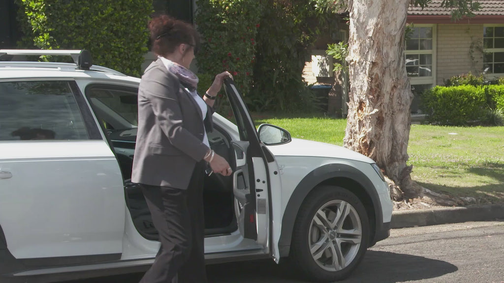 Woman stepping out of a white car on a suburban street, filmed as part of the Keyguard demonstration video.