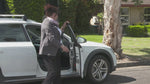 Woman stepping out of a white car on a suburban street, filmed as part of the Keyguard demonstration video.